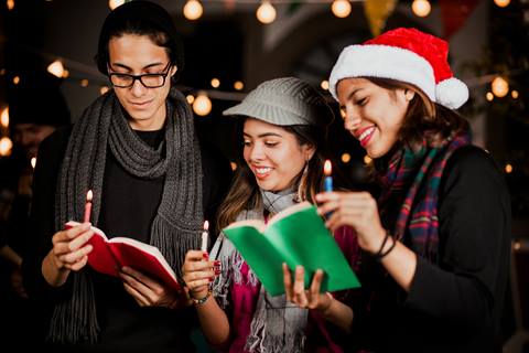 stock image of christmas carolers singing from caroling books