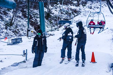 ski patrollers surrounding lift tower