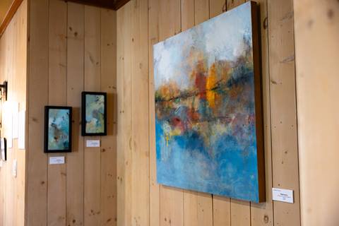 abstract paintings hanging on wood paneled wall