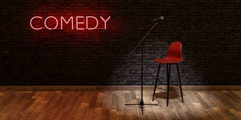 Microphone and bar chair on stage with comedy sign