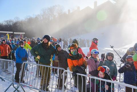 skiers wait in line for the lift on a sunny winter morning