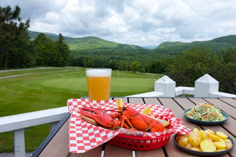 lobster dinner and sides with  beer and golf course view