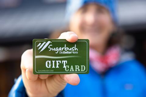 woman holding a sugarbush gift card out in front of her