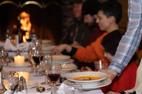 server putting down soup on fancy set table near fireplace