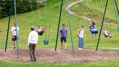 parents pushing kids on swings